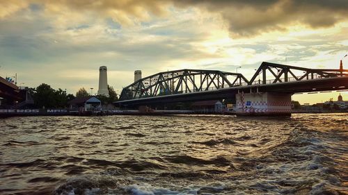 Low angle view of bridge over river against cloudy sky