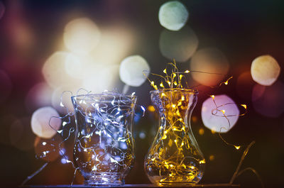 Close-up of illuminated string lights in glass containers