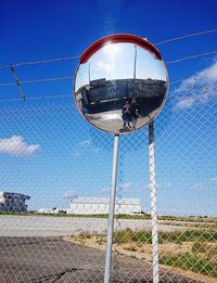 Low angle view of chainlink fence against clear blue sky