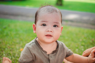 Close-up portrait of cute baby boy on field