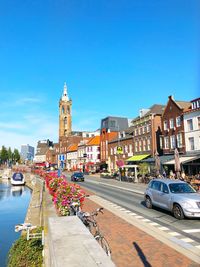 Vehicles on road by buildings against clear blue sky