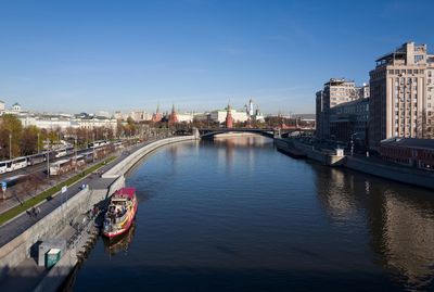 Bridge over river by buildings against sky in city