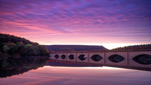 Bridge over river against sky during sunrise