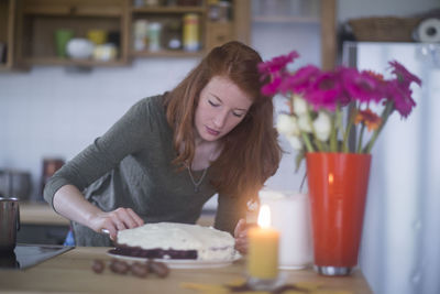 Young woman making birthday cake at home