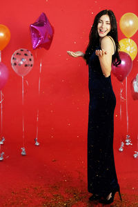Smiling young woman with red balloons