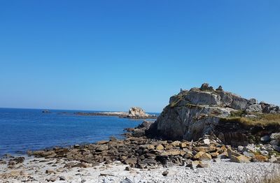 Rock formation on beach against clear blue sky