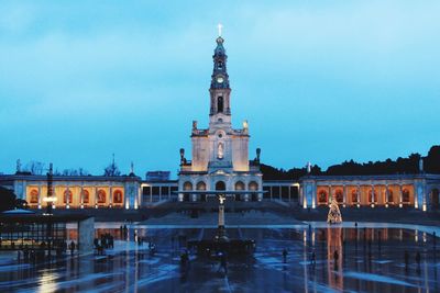 Fountain in city against sky at dusk