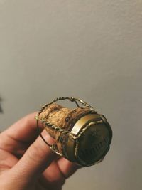 Close-up of hand holding clock against wall