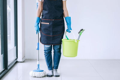 Low section of cleaner with mop and bucket on tiled floor