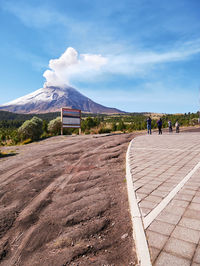 People on road by mountain against sky