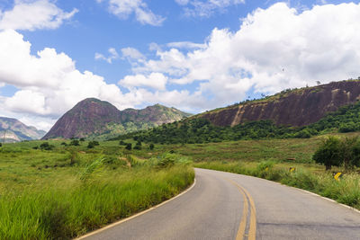 Road leading towards mountains against sky