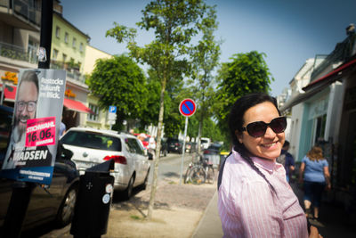 Portrait of smiling young woman standing on road in city