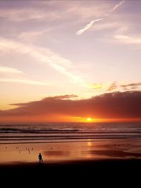 Silhouette man standing on beach against sky during sunset