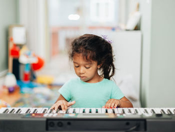 Cute girl learning piano at home