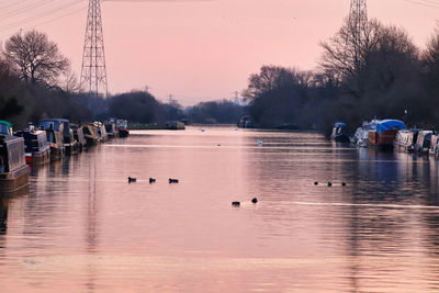 Sailboats in river against sky during sunset