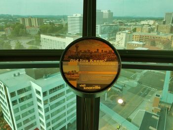 Close-up of text on glass window against buildings in city