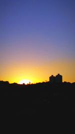 Silhouette buildings against clear sky during sunset