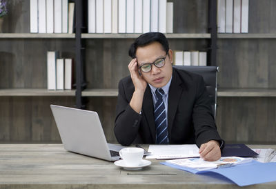 Mid adult man using mobile phone while sitting on table