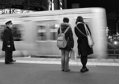 Rear view of commuters waiting at station platform