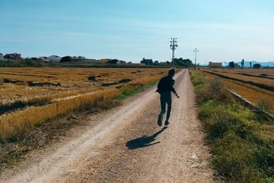 Rear view of man walking on road