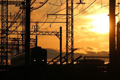 Low angle view of electricity pylon against sky during sunset