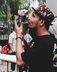 Side view of man wearing hat drinking coffee outdoors