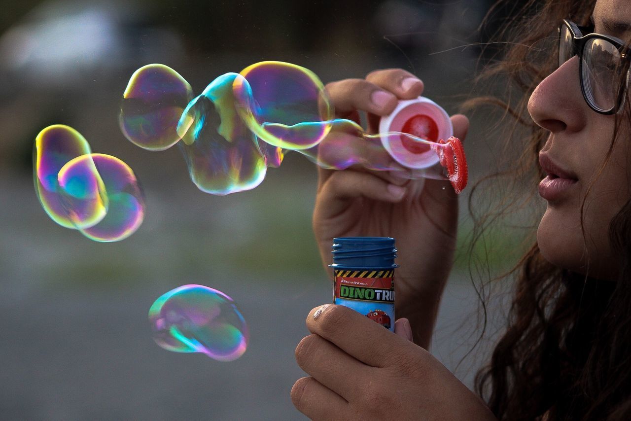 FULL LENGTH OF WOMAN HOLDING BUBBLES IN BUBBLE