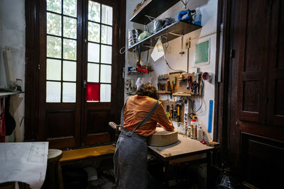 Unrecognized young woman in her luthier workshop.