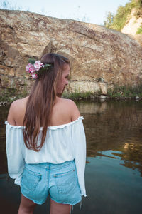 Beautiful woman standing by lake against plants