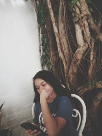 Portrait of a young woman sitting on tree trunk