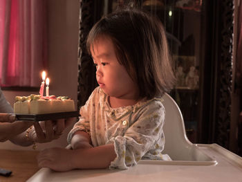 Cropped hands of mother holding birthday cake by daughter at home