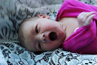 Cute baby crying while lying on bed