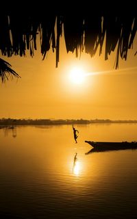 Silhouette man jumping on lake against clear sky during sunset