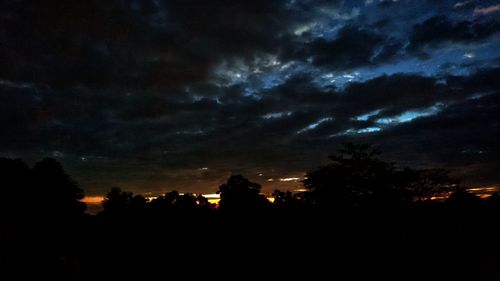 Silhouette of trees against cloudy sky