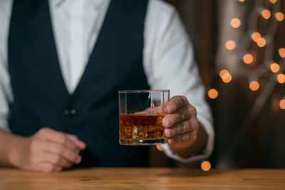 Midsection of man holding beer glass on table