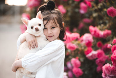 Happy child girl 3-4 year old holding pet dog over nature background closeup. looking at camera. 