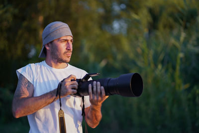 Young man looking away holding camera