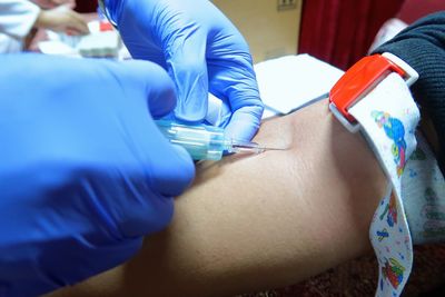 Cropped hands of doctor injecting patient in hospital