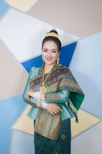 Portrait of smiling young woman standing against wall