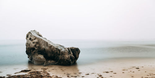 Rocks on beach against clear sky