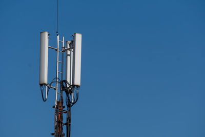 Low angle view of communications tower against clear blue sky