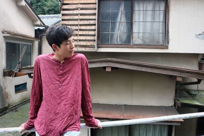 Three quarter length of teenage boy standing against crumbling building