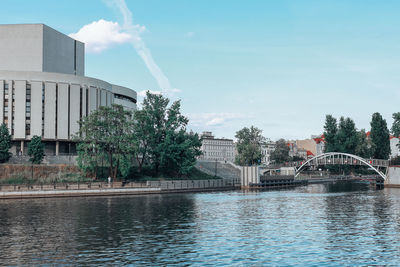 Bridge over river by buildings against sky