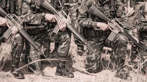 Low section of army soldiers with rifle on field