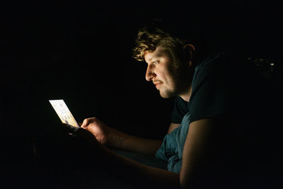 Side view of young man using mobile phone