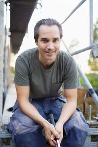 Portrait of confident man sitting outside house being renovated