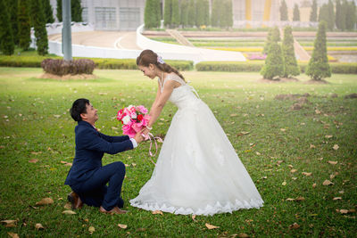 Bridegroom giving bouquet to bride on field