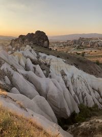 Rock formations on landscape against sky during sunset