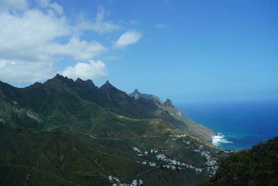 Scenic view of sea and mountains against blue sky