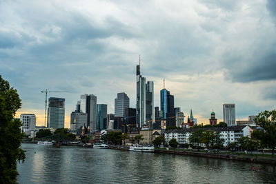 City at waterfront against cloudy sky